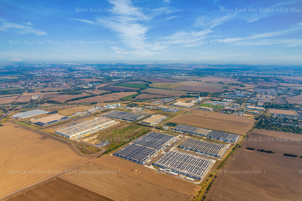 7_Osterweddingen_West_amazon_A14_Magdeburg-1630 | Blick aus dem hoch fliegenden Tragschrauber auf den Gewerbestandort Osterweddingen südlich von Magdeburg. Die weite Perspektive erfasst große Teile des Gewerbegebietes und macht zugleich die Autobahn A14 als wichtige Verkehrsachse sichtbar.Am Horizont ist Magdeburg zu erkennen. Dadurch wird die räumliche Lage Osterweddingens besonders deutlich: ein bedeutender Gewerbestandort südlich der Landeshauptstadt, eingebunden in die regionale Infrastruktur und direkt an die Autobahn angebunden.Die Aufnahme entstand im Rahmen der Standortdokumentation für den Landkreis Börde. Im Gegensatz zu den näheren Aufnahmen zeigt dieses Luftbild bewusst den gesamten Standort und seine Einbindung in die Umgebung.Gerade solche großräumigen Aufnahmen eignen sich für Standortmarketing, weil sie nicht nur einzelne Unternehmen oder Gebäude zeigen, sondern die Dimension eines Gewerbestandortes und seine Lage im regionalen Wirtschaftsraum sichtbar machen. - Realisiert mit Pictrs.com
