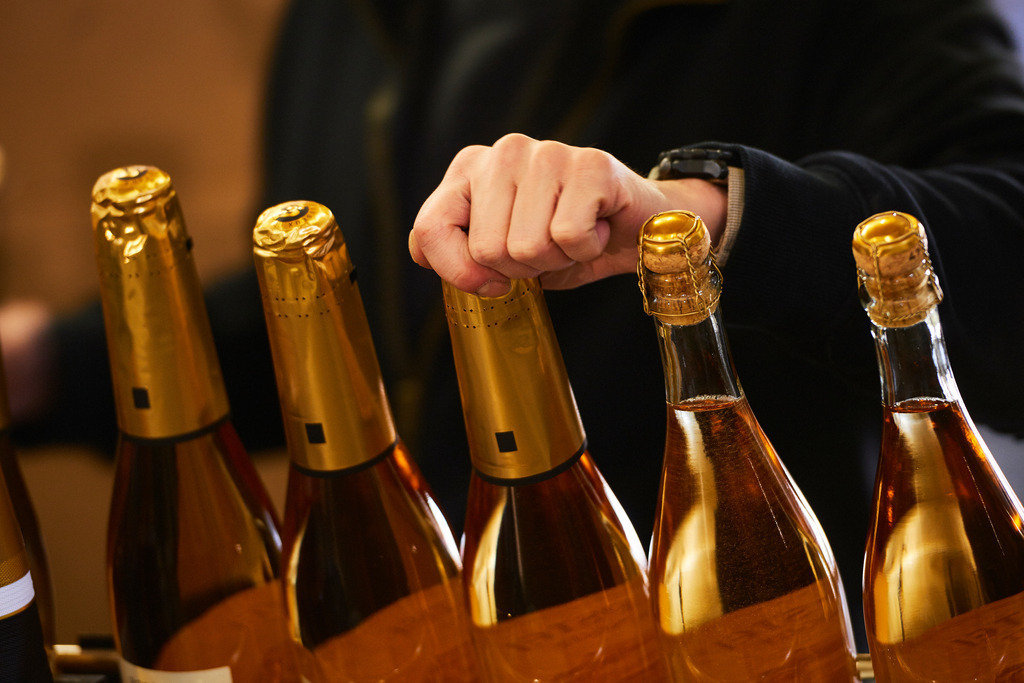 Sektkellerei Szigeti | Gols, Austria - February 19, 2018: Sektkellerei Szigeti; Sektflaschen werden von einem Mitarbeiter mit Sekt-Kappen bestückt. - Realisiert mit Pictrs.com