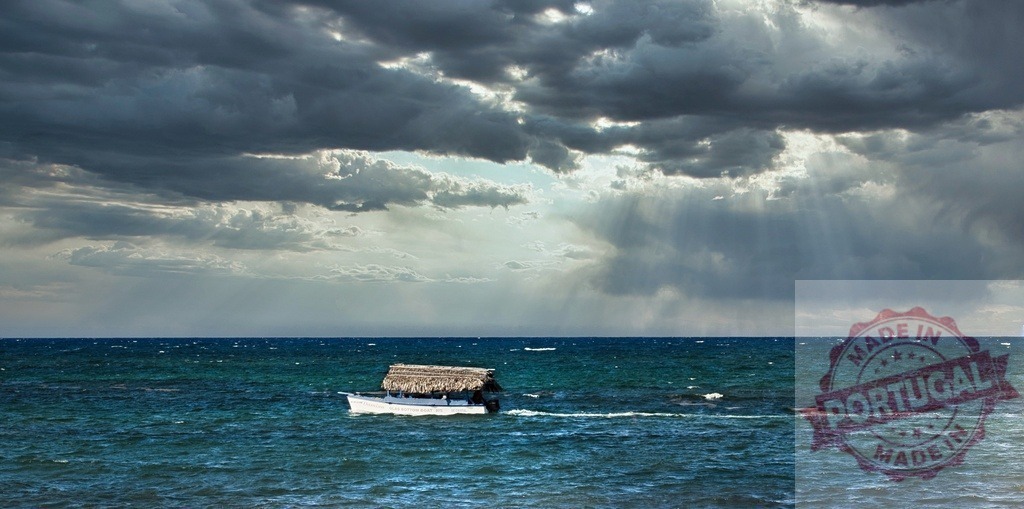 Boat with thatched roof navigating stormy ocean under sunrays | Small boat sailing on a rough sea with dark storm clouds and sunbeams - Realized with Pictrs.com