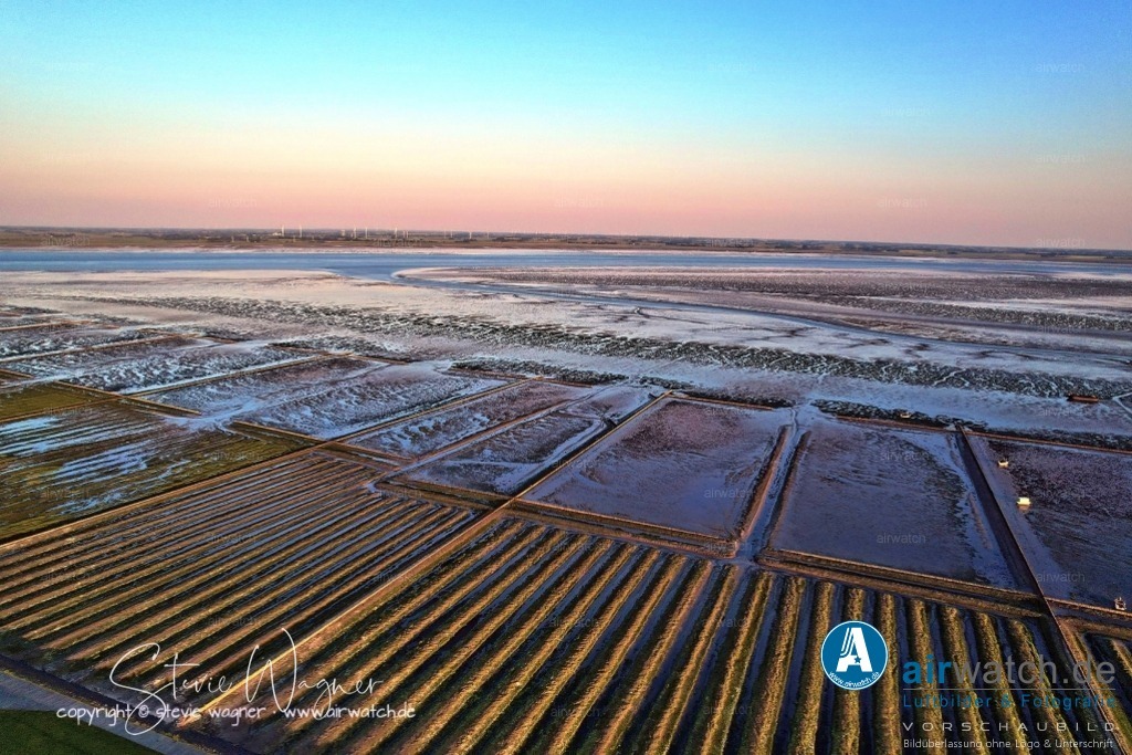 Luftbild Nordstrand, LangerDeich, Dreisprung, An de Wehl, Evensbüller Chaussee, Husumer Bucht | Luftbild Nordstrand, LangerDeich, Dreisprung, An de Wehl, Evensbüller Chaussee, Husumer Bucht - Die Landgewinnung auf Nordstrand ist Teil einer langen Tradition des Deichbaus und der Rekultivierung von Wattflächen. Bereits im Mittelalter begannen die Bewohner, Deiche zu errichten, um sich vor Sturmfluten zu schützen und neues Ackerland zu gewinnen. Im Laufe der Jahrhunderte wurden große Teile des Wattenmeers eingedeicht, wodurch die Halbinsel kontinuierlich vergrößert wurde.