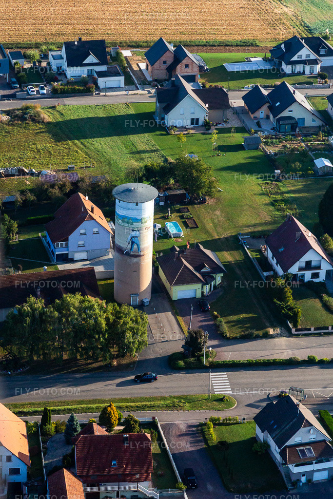 Aerial view: Water tower with painting in Schœnenbourg in the state Bas-Rhin, France. – Photo: IMG_139239.jpg taken on 10/01/2023 by Werner Riehm/FLY-FOTO.com – Resolution of the original: 2690 x 4034 px