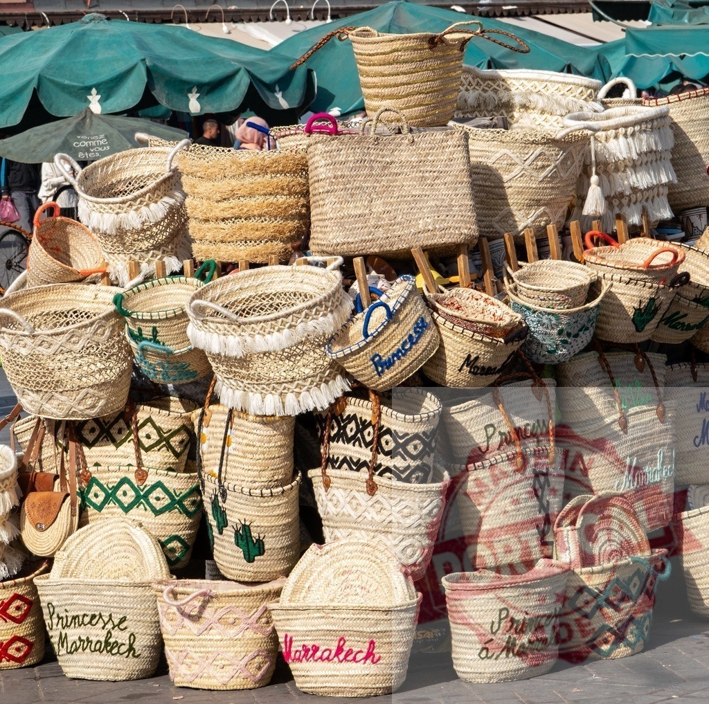 Display of handmade straw baskets with colorful decorations in Marrakech | Large group of wicker baskets for sale in a traditional Moroccan market in Marrakech - Realized with Pictrs.com
