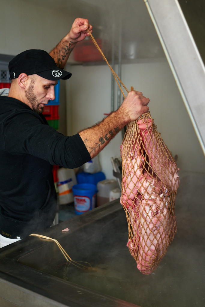 Fleischerei Dormayer | Langenzersdorf, Austria - February 12, 2019: Fleischerei Dormayer - Blutwurst Herstellung; ein Netz mit Schweinsköpfen wird in den Kochtopf gehängt. - Realisiert mit Pictrs.com