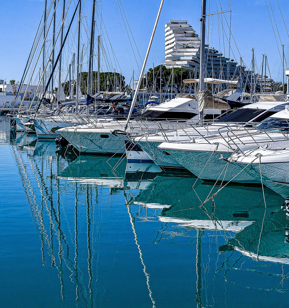 Wandbild Kunstdruck Poster Exklusiver Yachthafen – Maritime Fotokunst in Blau | Bringen Sie die Eleganz und das unbeschwerte Lebensgefühl eines exklusiven Yachthafens direkt an Ihre Wand. Dieses stilvolle maritime Wandbild zeigt weiße Luxusyachten, die friedlich im glitzernden, tiefblauen Wasser liegen, umgeben von eleganter Küsten-Kulisse. Ein absolutes Highlight für Liebhaber von modernem Yacht-Design, weiten Reisen und sommerlicher Ästhetik. Gedruckt auf Premium-Leinwand, feinstem Alu-Dibond oder kristallklarem Acrylglas garantiert dieses Motiv eine beeindruckende Tiefenwirkung in Wohnzimmer, Büro oder Lounge. - Realisiert mit Pictrs.com