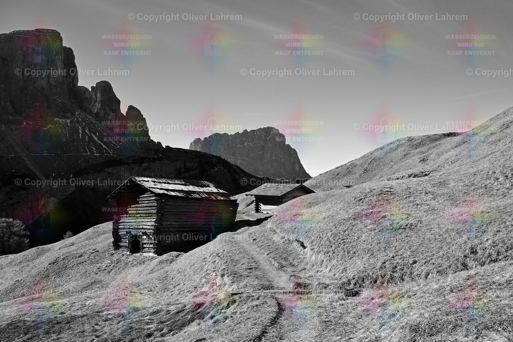 Herbstidylle in den Dolomiten | Ein Wanderweg führt an schönen Holzhütten vorbei und entlang herbstlicher Bergwiesen in Richtung des sichtbaren Langkofels 