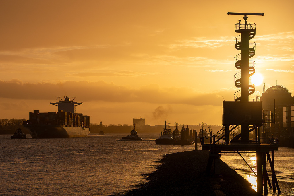 Goldene Stunde im Hafen | Eine Aufnahme des Hamburger Hafens in einer intensiven Abendstimmung. Das Bild zeigt die markanten Silhouetten der Radartürme und Schiffe gegen den brennenden Himmel. Ein Motiv, das durch den starken Kontrast und das natürliche Licht an der Elbkante besticht. - Realisiert mit Pictrs.com