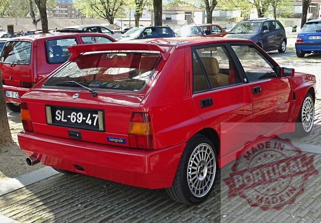 Red Lancia Delta HF Integrale rally car parking outdoors | Red Lancia Delta HF Integrale, an iconic Italian rally car, parked in an outdoor lot - Realisiert mit Pictrs.com