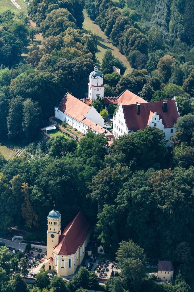 dr__0016374.jpg | NEUBURG AN DER KAMMEL 03.08.2018 Schloss Neuburg an der Kammel in Neuburg im Bundesland Bayern. Zusammen mit der Pfarrkirche St. Mariae Himmelfahrt bestimmt der Gebäudekomplex aus dem dreigeschossigen Hauptbau mit Satteldach und zinnenbesetztem Giebel, zweischiffiger Kapelle, Turm und Wirtschaftsgebäuden, das Ortsbild. Das Schloss wurde 1552 erbaut und heute als Gastronomiebetrieb genutzt. // Castle Neuburg an der Kammel in Neuburg in the state of Bavaria. The historic building complex with the parochial church St. Mariae Himmelfahrt beneath it and the three storey main building, the gabled roof with battlements, the two ship chapel and the tower and outbuildings,  is a landmark of the village. The castle was built in 1552 and is used as a restaurant today. Foto: Daniel Reiter