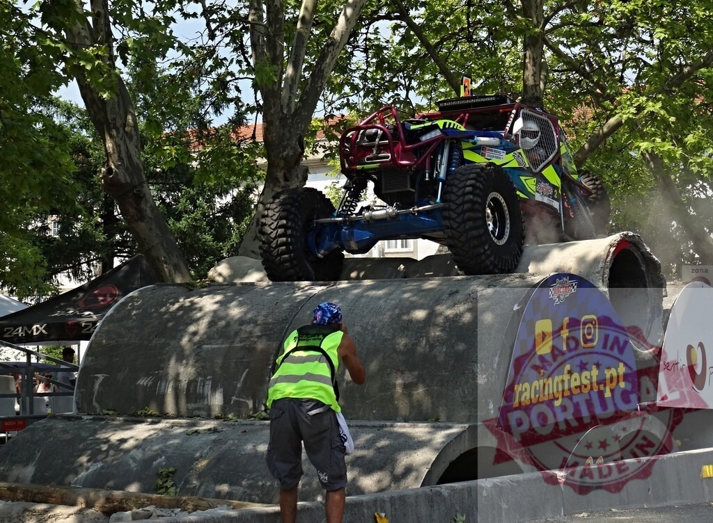 Buggy jumping over concrete pipes during an outdoor motorsport competition | Professional driver performing stunts with a buggy during an outdoor motorsport competition - Realized with Pictrs.com