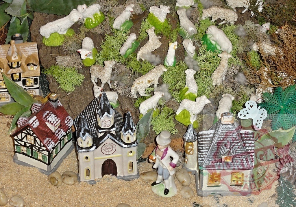Shepherd figurine standing near miniature houses and flock of sheep | Shepherd figurine standing near miniature houses and flock of sheep grazing on a miniature hill in a christmas nativity scene - Realisiert mit Pictrs.com