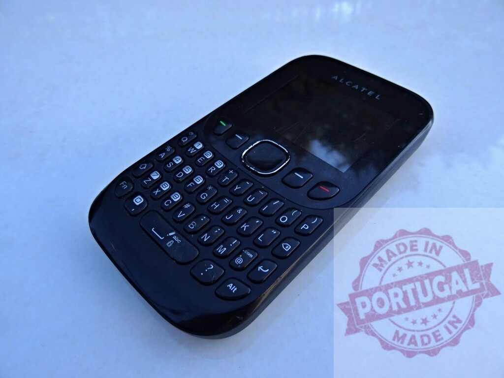 ALCATEL phone showing its qwerty keyboard and resting on a white surface | Classic black ALCATEL mobile phone with full keyboard on a white surface - Realisiert mit Pictrs.com