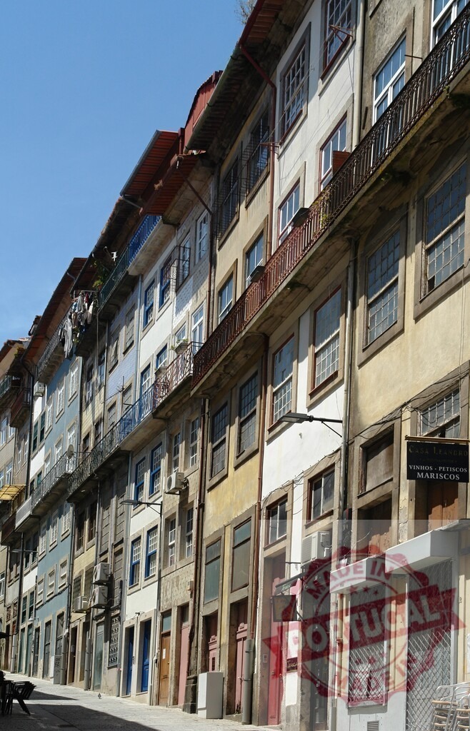 Porto street with old colorful Ribeira district buildings | Historic Ribeira district street featuring old residential and commercial architecture under a clear blue sky - Realized with Pictrs.com