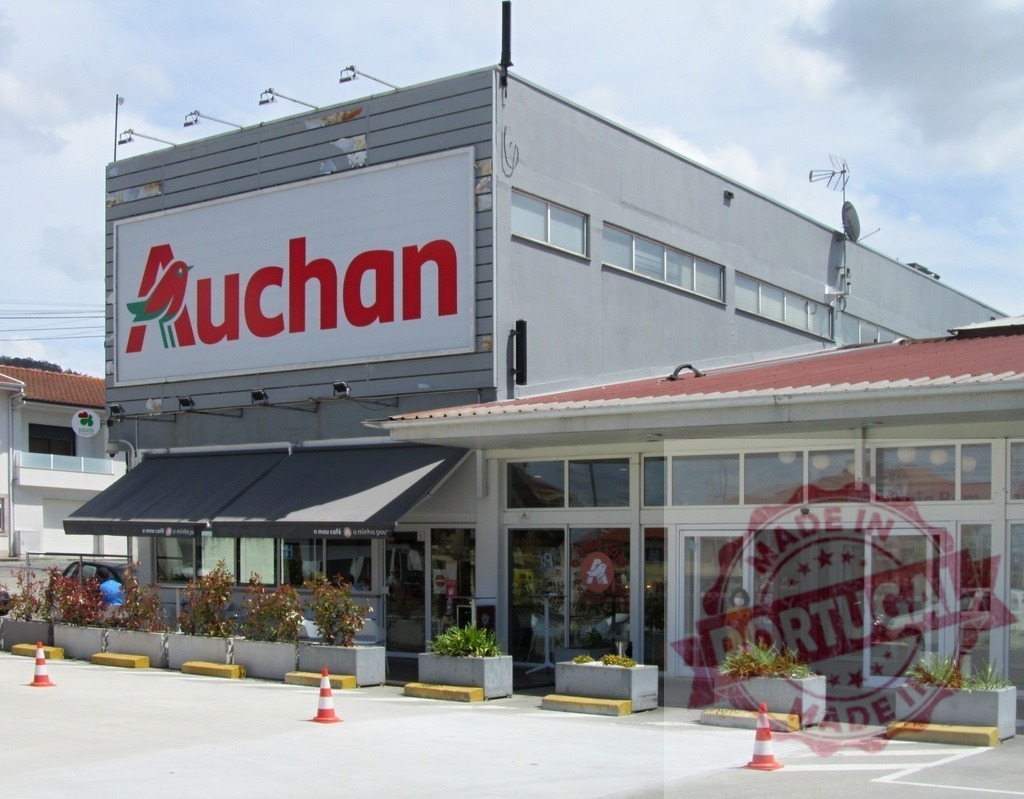Modern Auchan supermarket storefront with visible signage and outdoor parking | Contemporary Auchan retail building exterior with entrance, logo, and parking area - Realized with Pictrs.com