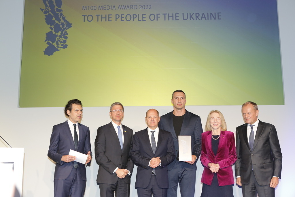 M100 Media Award: „Preis der europäischen Presse“ in Potsdam für das Ukrainische Volk verliehen. | Mit dem M100 Media Award, der sich als „Preis der europäischen Presse“ versteht, wird in diesem Jahr das Ukrainische Volk ausgezeichnet. Die Auszeichnung nimmt stellvertretend Wladimir Klitschko in der Orangerie im Park Sanssouci entgegen. Das Bild zeigt Mike Schubert, Olaf Scholz,Wladimir Klitschko, US-Botschafterin Amy Gutmann und Donald Tusk.