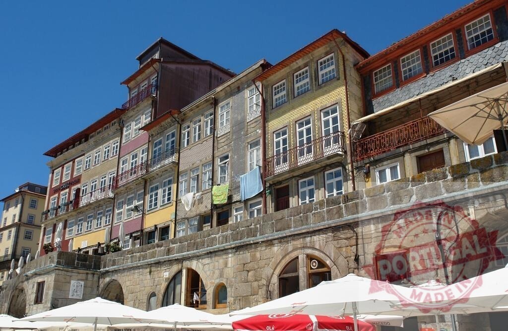 Ribeira district colorful buildings along Douro River Porto | Porto's historic Ribeira district showcasing traditional houses with laundry drying under blue sky - Realized with Pictrs.com