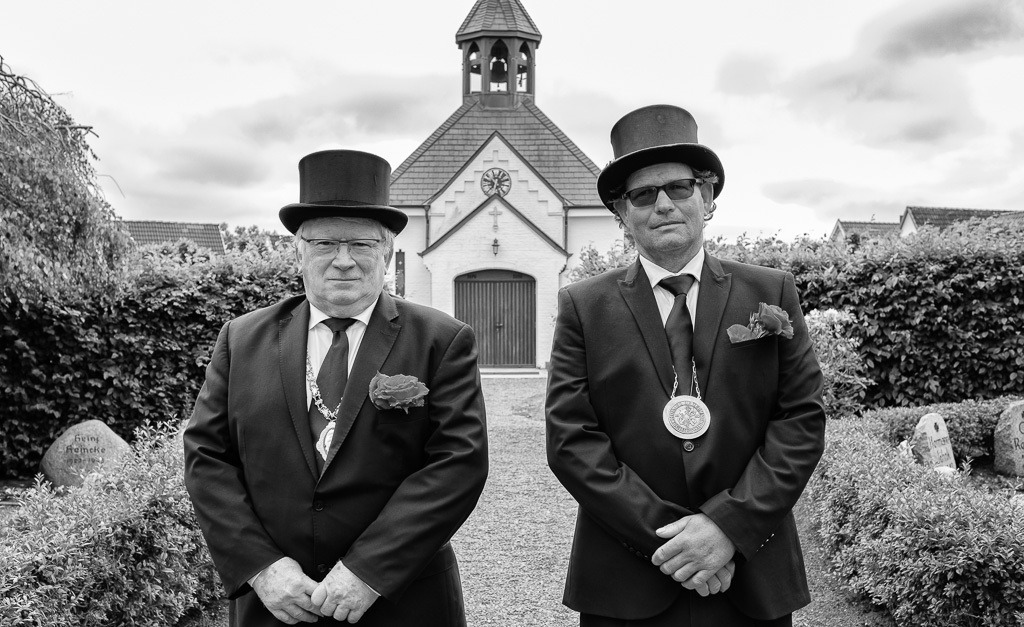 fischer-2020-126 | Wegen der COVID-19-Pandemie konnte das jährliche Fest der Holmer Beliebung in Schleswig 2020 nicht im üblichen Rahmen stattfinden. Die traditionelle Veranstaltung blieb auf eine würdevolle Totenehrung am 14.6.2020 auf dem Friedhof der ehemaligen Fischersiedlung beschränkt.  Das Bild entstand nach der Kranzniederlegung und zeigt die Älterleute der Holmer Beliebung vor der Friedhofskapelle: links Kai-Uwe Schleimer, 1. Ältermann, und daneben Matthias Nanz, 2. Ältermann. - Realisiert mit Pictrs.com