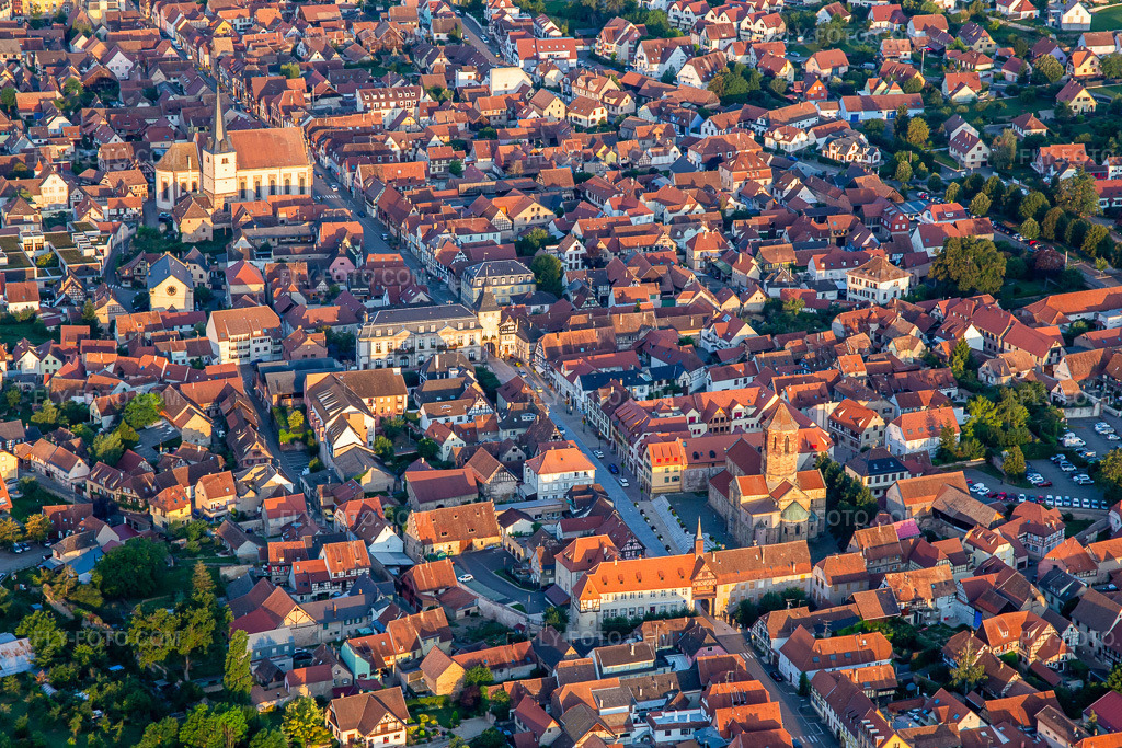 Aerial view: Rue du Gén de Gaulle with Porte basse ou Porte de la Vierge, Tour de l'Ecole, Tour de l'Horloge ou Zittgloeckel and Eglise catholique Saint-Etienne in Rosheim in the state Bas-Rhin, France. – Photo: IMG_137984.jpg taken on 08/19/2023 by Werner Riehm/FLY-FOTO.com – Resolution of the original: 5189 x 3459 px – Bienvenue à Rosheim