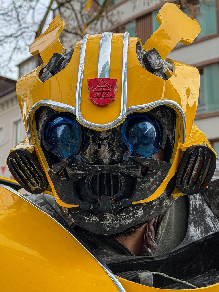 Basel Dreiländereck – Urbanes Bumblebee Cosplay Wandbild | Exklusive Urban- und Street-Fotografie aus Basel: Dieses High-End Wandbild fängt die faszinierenden Details eines lebensechten Bumblebee-Cosplays ein. Jede Schramme, die leuchtend gelbe Lackierung und die mechanischen Strukturen des Transformers-Helms werden messerscharf und haptisch wiedergegeben. Ein spektakulärer Blickfang in Galeriequalität auf Alu-Dibond oder Acrylglas – das ultimative Statement-Piece für Gaming-Zimmer, Heimkinos und Sci-Fi-Fans. - Realisiert mit Pictrs.com