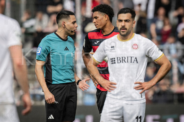 Viktoria Koeln vs. SV Wehen Wiesbaden, 11.04.2026 | KOELN, GERMANY - APRIL 11, 2026:  referee Cengiz Kabalakli (Gelsenkirchen) in discussions with Benjamin Zank (Viktoria Köln, 23) during the 3rd division match between Viktoria Koeln vs. SV Wehen Wiesbaden at the Sportpark Hoehenberg on matchday 7 on April 11, 2026 in Koeln, Germany. DFL REGULATIONS PROHIBIT ANY USE OF PHOTOGRAPHS AS IMAGE SEQUENCES AND/OR QUASI-VIDEO.