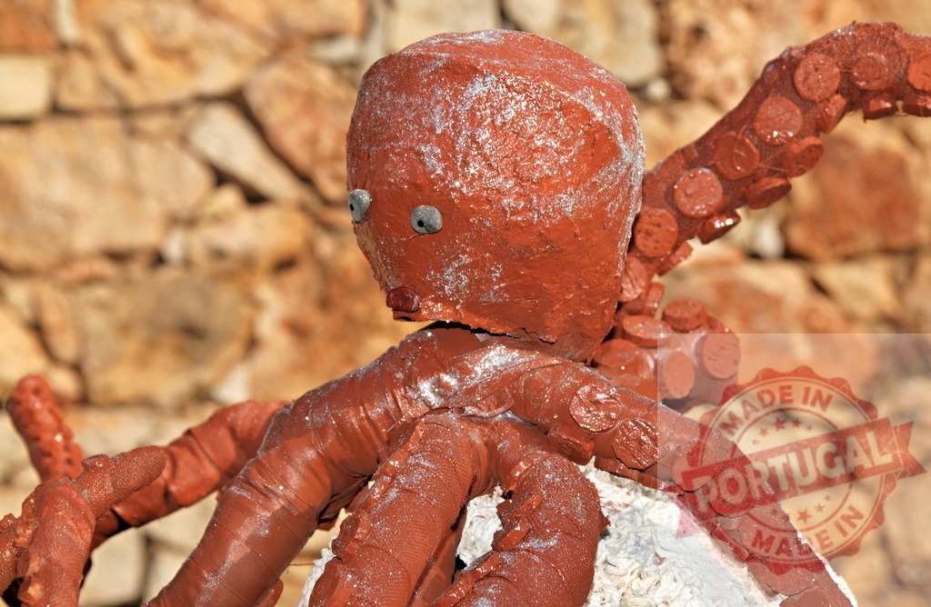 Handmade octopus sculpture with googly eyes standing outdoors | Terracotta-colored octopus sculpture features googly eyes, creating a whimsical art piece - Realized with Pictrs.com
