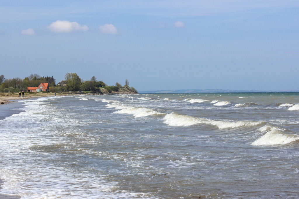 Wandbild: Wellen am Ostseestrand | Dieses Wandbild im Querformat zeigt schöne Wellen mit Schaumkrone am Strand in Norgaardholz. In der Ferne ist die Steilküste zu sehen.  - Realisiert mit Pictrs.com