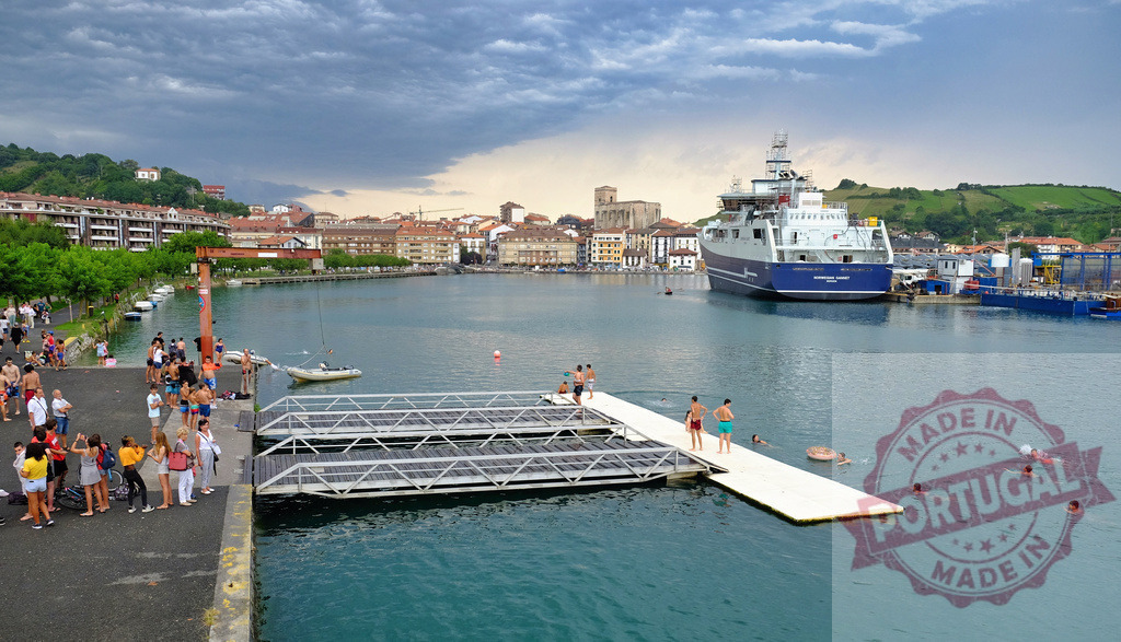 People swimming and relaxing in Zumaia harbor in Spain | People enjoying a summer day swimming in the harbor surrounded by the town and boats - Realisiert mit Pictrs.com