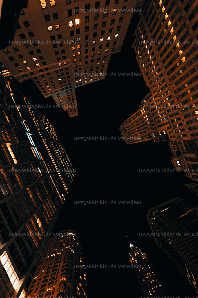 Umzingelt von Giganten – Manhattan schwarz wie die Nacht und doch so warm beleuchtet | Der Himmel fast schwarz, die Nacht tief und geheimnisvoll – und doch erstrahlen die Wolkenkratzer in warmem Licht, das ihre monumentale Präsenz betont. Dieses Foto wurde vom Boden aus aufgenommen, um die überwältigende Größe der Gebäude einzufangen, die sich wie Giganten um einen herum erheben. Die Kontraste zwischen der Dunkelheit des Himmels und den leuchtenden Fassaden schaffen eine dramatische Kulisse, die die Kraft und Schönheit von Manhattan in ihrer reinsten Form zeigt. Es ist ein Moment, der die eigene Kleinheit spürbar macht und gleichzeitig die Faszination für die Architektur und das Leben dieser Stadt weckt.