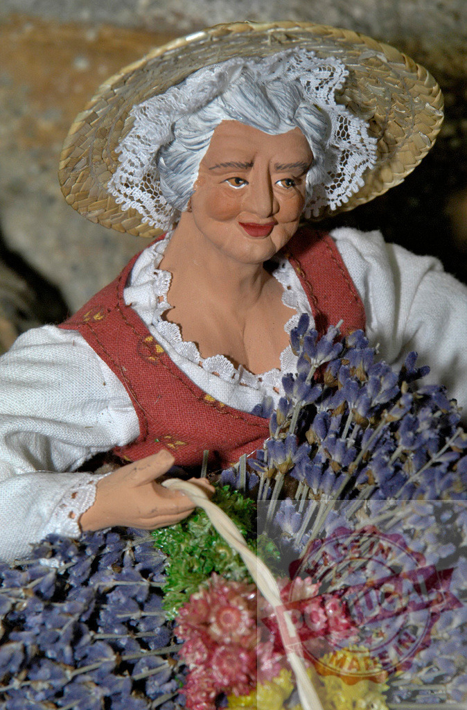 Elderly woman farmer figurine holding lavender and straw hat | Terracotta figurine of smiling elderly woman farmer holding lavender bouquets and wearing straw hat - Realized with Pictrs.com