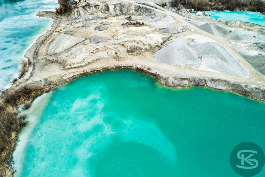 Zugefrorene Kiesgrube aus der Luft – Faszinierende Winterlandschaft als Drohnenaufnahme | Beeindruckende Luftaufnahme einer zugefrorenen Kiesgrube im Winter. Die Drohnenfotografie zeigt türkisblaues Eis und abstrakte Naturmuster aus der Vogelperspektive – einzigartige Winterlandschaft von oben. - Realisiert mit Pictrs.com