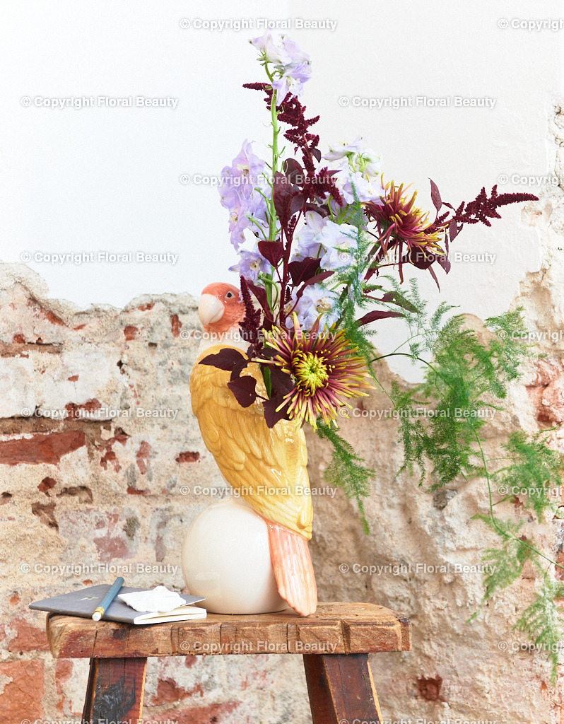 Wandbild Dahlien mit Amaranth und Rittersporn vor Mauer | Strauß aus Dahlien mit Amaranth und Rittersporn vor abgebröckeltem Putz in Papageienvase. Sehr besonderes Motiv als Kunstdruck auf Leinwand oder Holz zu empfehlen.  - Realisiert mit Pictrs.com