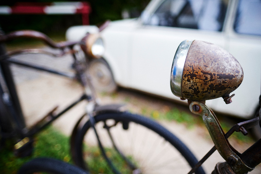 Rostige Alte Räder, im Hintergrund ein Trabi | Mönchhof, Austria - October 06, 2021: Dorfmuseum Mönchhof; Rostige Alte Räder, im Hintergrund ein Trabi vor der Zollkontrolle. - Realisiert mit Pictrs.com