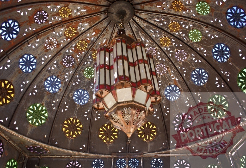 Moroccan lantern hanging from ornate stained glass dome | Intricate Moroccan style lantern decorating an iron dome with colorful stained glass details - Realized with Pictrs.com