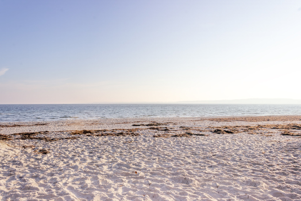 Strandlinie im Morgenlicht – Natürliche Ruhe | Dieses minimalistische Meeresmotiv zeigt eine ruhige Strandszene mit hellem Sand, feinen Strukturen und einer stillen Wasserfläche, die sanft in den Horizont übergeht. Das warme Licht verleiht dem Motiv eine weiche, natürliche Stimmung und unterstreicht die klare, offene Bildsprache. Die Komposition wirkt beruhigend und zeitlos, ideal für moderne Räume, die maritime Ruhe ausstrahlen sollen. Als Wandbild erhältlich auf Alu‑Dibond und weiteren hochwertigen Materialien.
