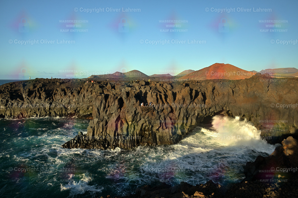 Los Hervideros | Die markanten Lavaklippen von "Los Hervideros" mit den Vulkanen des Nationalpark Timanfaya im Abendrot