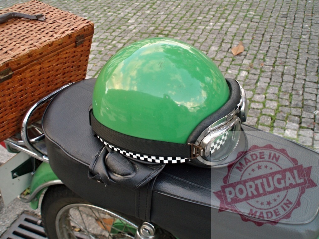 Green helmet with goggles is lying on a motorcycle seat | Shiny green helmet with goggles and checkered strap is lying on a black motorcycle seat with wicker basket on the back - Realized with Pictrs.com