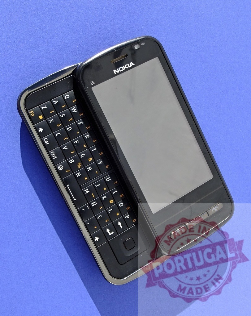 Nokia C6 sliding mobile phone showing keyboard on blue background | Old Nokia C6 sliding phone revealing qwerty keyboard on vibrant blue background - Realisiert mit Pictrs.com