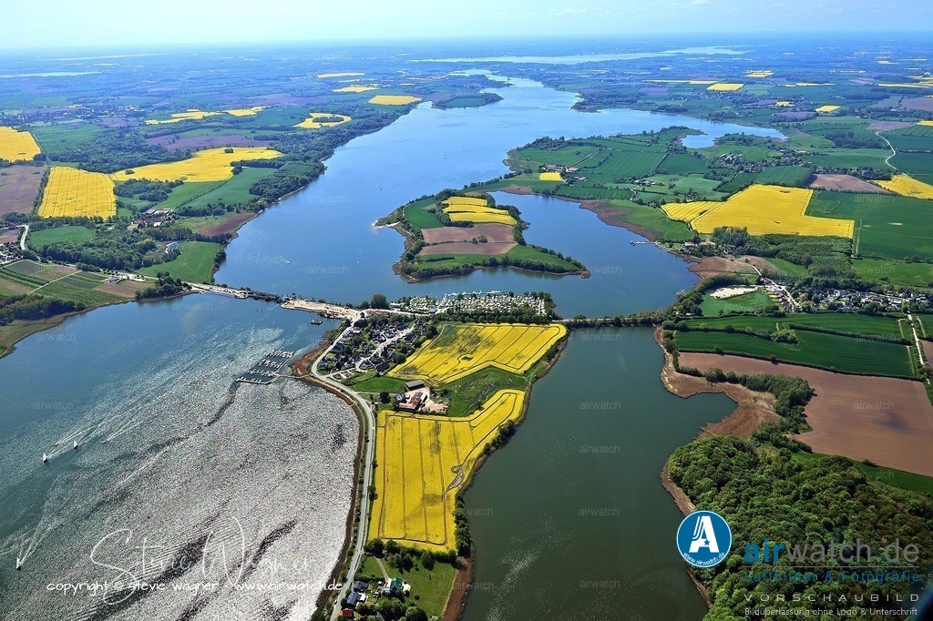 Luftbild Ostseefjord Schlei, Gunnebyer Noor, Badestrand Gunneby, Landschaftsschutzgebiet Schwansener Schleilandschaft, Schleibrücke Lindaunis | Lindau, ein Ortsteil der Gemeinde Boren in Schleswig-Holstein, liegt am sagenumwobenen Ufer der Schlei und war im 19. Jahrhundert Teil der historischen Landschaft Angeln. Die Region ist seit der Jungsteinzeit besiedelt, was durch 13 Hünengräber im Gemeindegebiet belegt ist. Im 19. Jahrhundert wurde die St. Marien-Kirche in Boren, die ursprünglich in der ersten Hälfte des 13. Jahrhunderts errichtet wurde, stilrein romanisch erhalten, nachdem barocke Elemente zwischen 1938 und 1950 entfernt wurden. Die Kirche ist ein zentraler Bestandteil der historischen Landschaft, die im 19. Jahrhundert auch durch die Entwicklung der Schleiregion geprägt war.