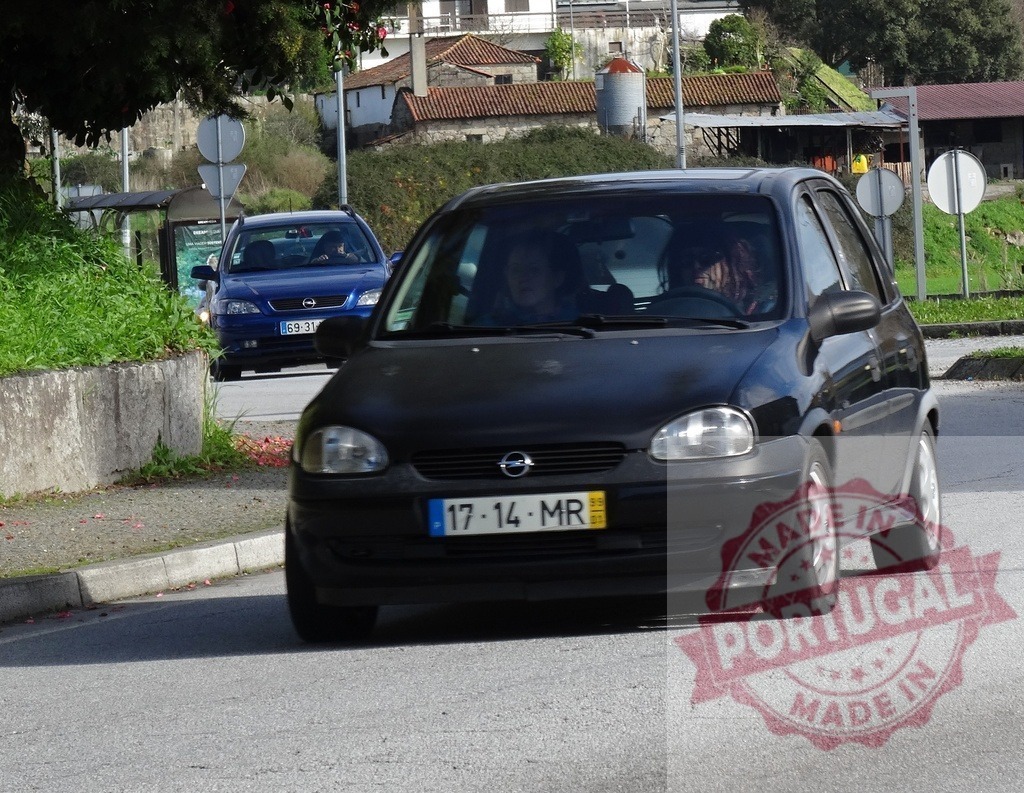 Everyday driving Opel Corsa hatchback on street | Black Opel Corsa car driving on a street with another blue car in background - Realisiert mit Pictrs.com