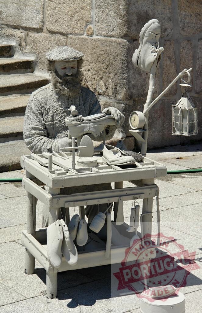 Street performer acting as a shoemaker living statue. Porto - Portugal | Street performer coated in grey paint portraying a shoemaker at work - Realisiert mit Pictrs.com