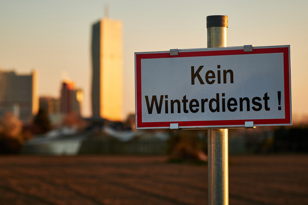 Hinweistafel Kein Winterdienst | Wien, Austria - March 31, 2021: Hinweistafel Kein Winterdienst, im Hintergrund eine große Wohnanlage. - Realisiert mit Pictrs.com