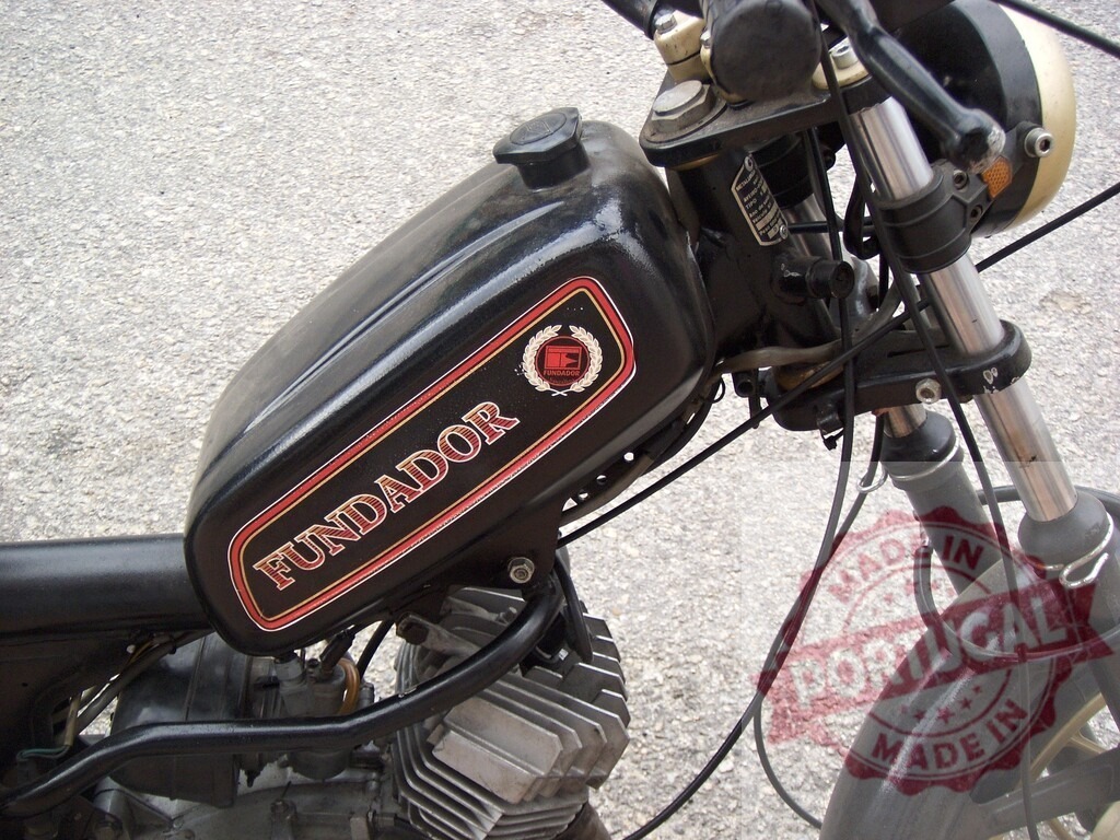 Fundador motorcycle fuel tank, close-up view showcasing vintage design | Close-up of a Fundador motorcycle's fuel tank, highlighting its vintage design and branding - Realized with Pictrs.com