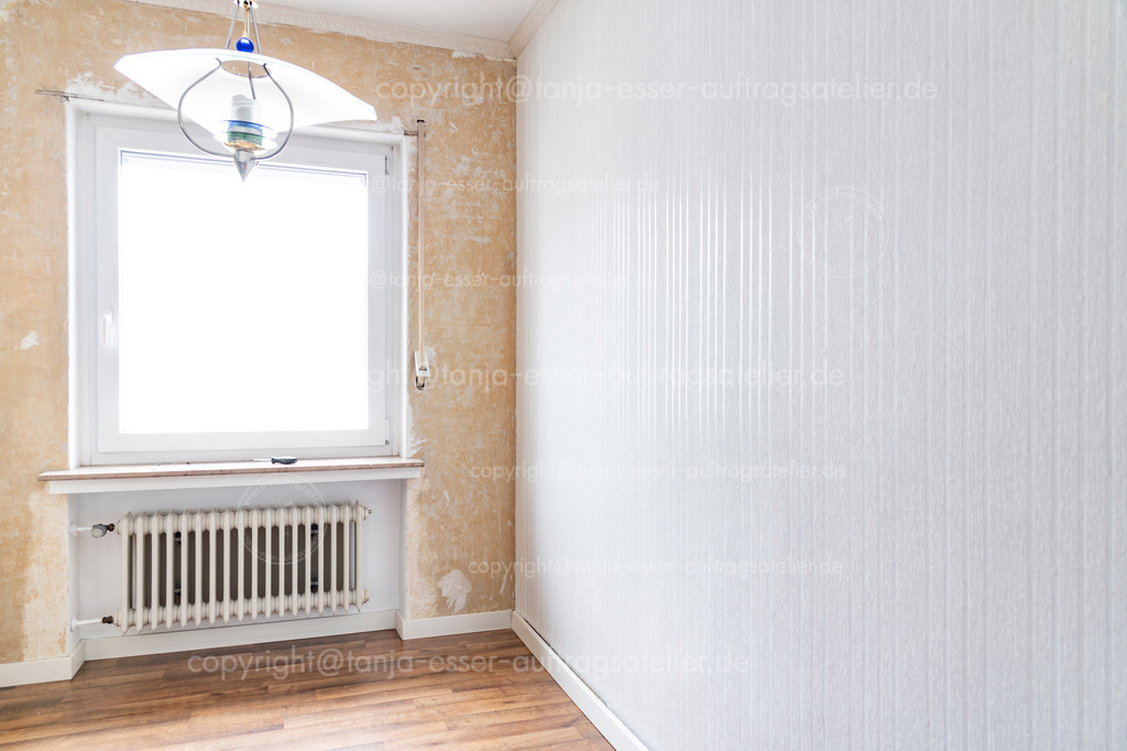 Frisch tapeziert, das Bild zeigt einen Vorher - Nachher - Effekt | Ein Raum wurde teilweise renoviert. Die linke Seite ist noch ohne Wandverkleidung. Rechts wurde eine neue gestreifte Tapete angebracht. Alte Rippenheizkörper. Copy Space.