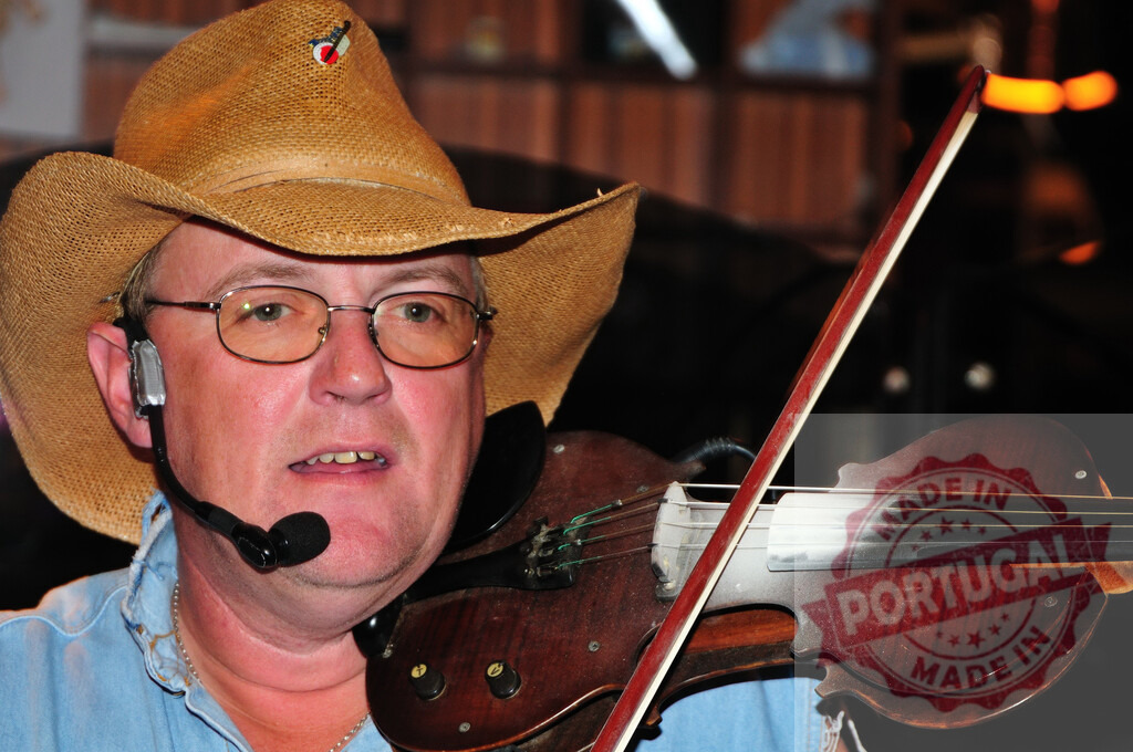 Musician playing electric violin wearing cowboy hat | Male musician wearing glasses and cowboy hat playing electric violin with microphone - Realized with Pictrs.com