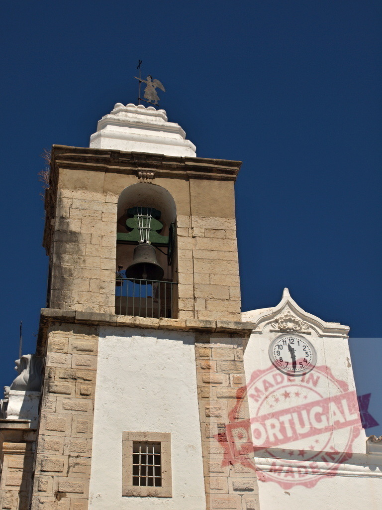 Bell tower with clock and angel under clear sky | Church bell tower showcasing traditional architecture, a working clock and an angel weathervane - Realisiert mit Pictrs.com