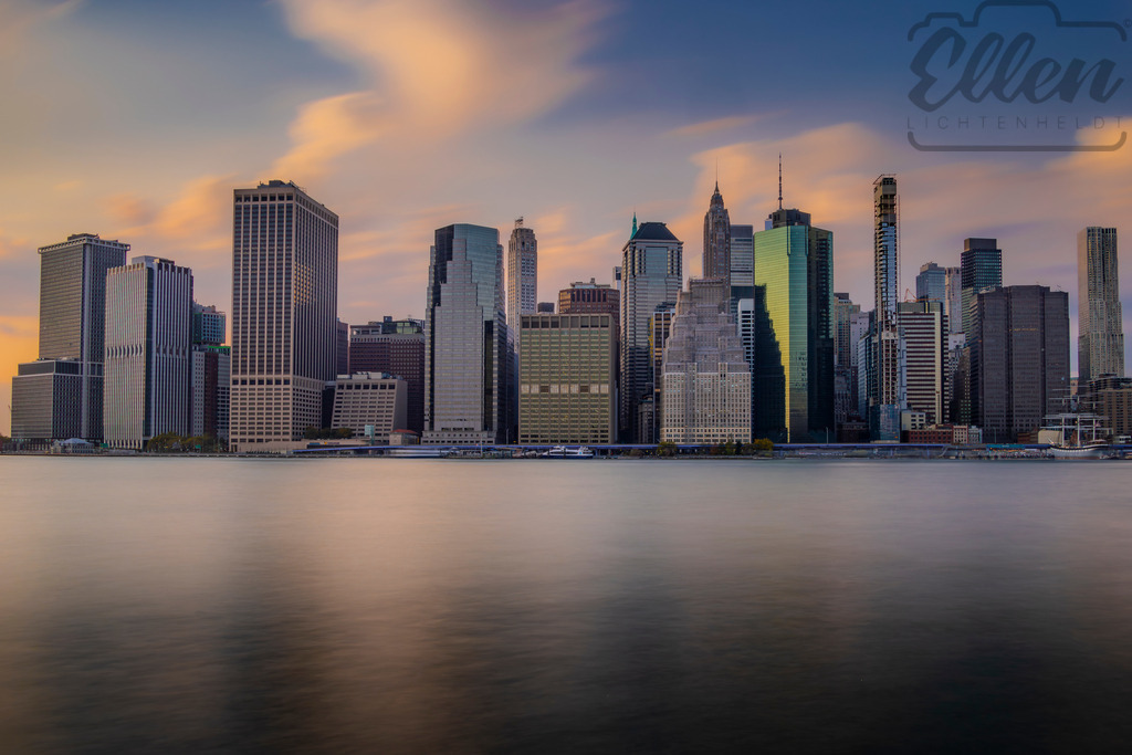 Evening Calm | The last light of day settles softly over Manhattan’s skyline, reflecting warm tones on the still surface of the East River. A quiet moment of balance between daylight and nightfall in the city that never sleeps. - Realisiert mit Pictrs.com