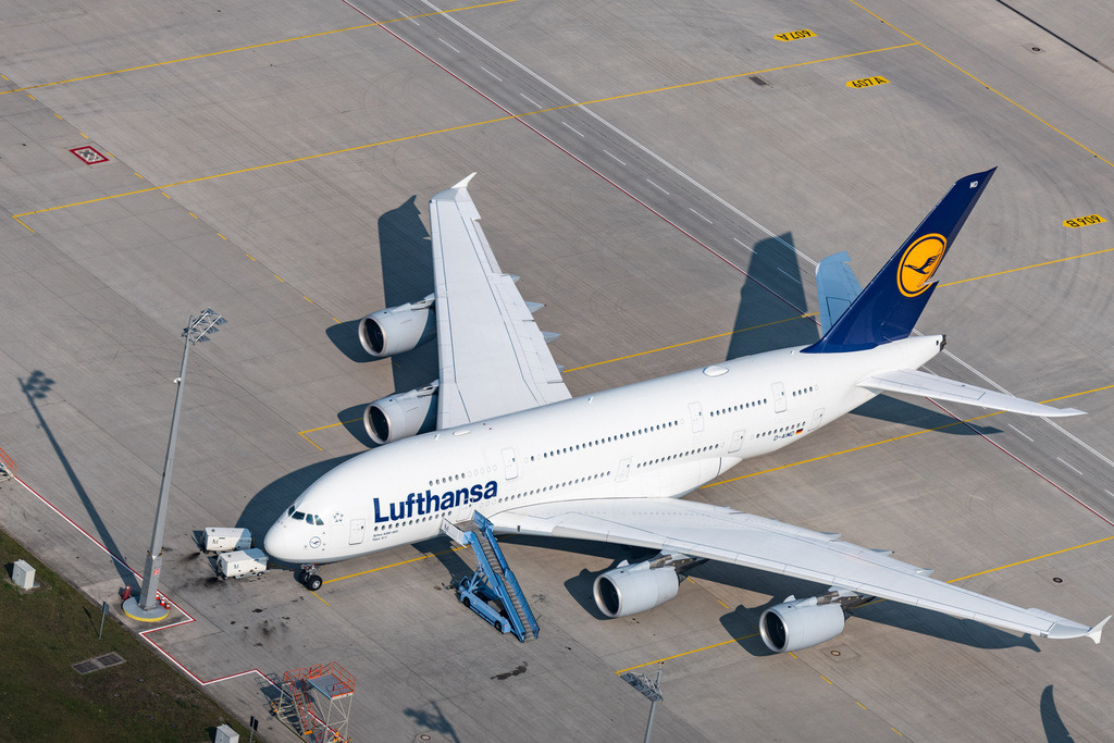 dr__0015393.jpg | HALLBERGMOOS 03.08.2018 Passagierflugzeug A380 der Lufthansa auf der Parkposition - Abstellfläche auf dem Flughafen München in Hallbergmoos im Bundesland Bayern, Deutschland. Weiterführende Informationen bei: Deutsche Lufthansa Aktiengesellschaft,  Flughafen München GmbH. // Passenger airplane A380 of Lufthansa in parking position - parking area at the airport Munic in Hallbergmoos in the state Bavaria, Germany. Further information at: Deutsche Lufthansa Aktiengesellschaft,  Flughafen Muenchen GmbH. Foto: Daniel Reiter