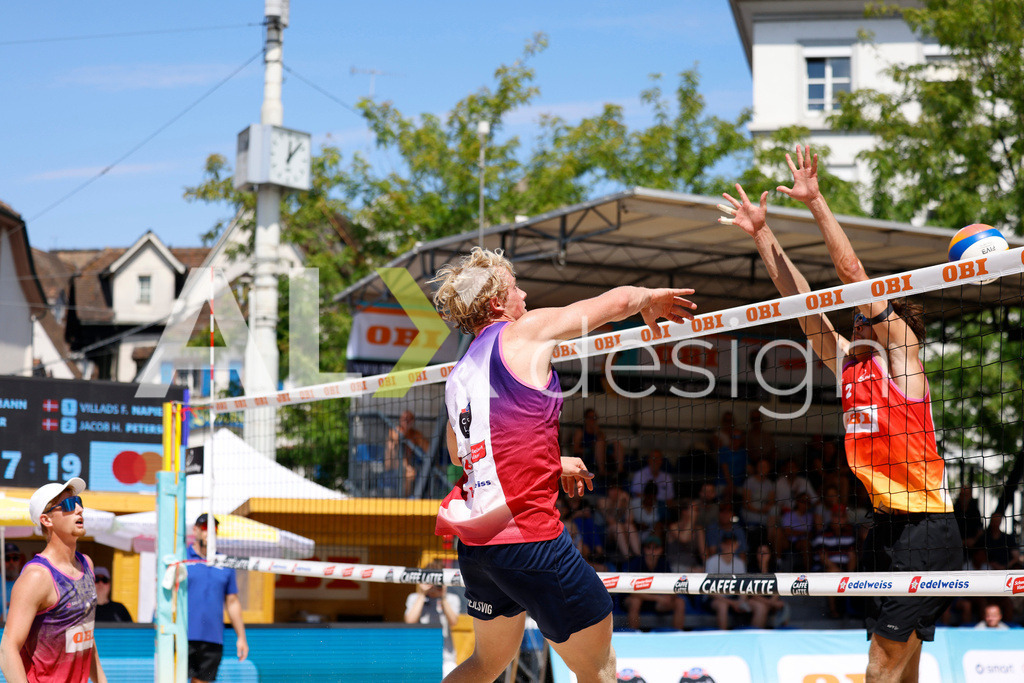 Obi BeachTour 2026 - Basel | BASEL, SWITZERLAND - JULY 18: JACOB HEJLSVIG PETERSEN (DEN) attack / spike against SIMON LEFFLER (SUI) block during the Obi BeachTour 2026 match between ALLEMANN / LEFFLER (SUI) and MASSEREY / SCHNEGG (SUI) at Barfüsserplatz on July 18, 2026 in Basel, Switzerland. - Realisiert mit Pictrs.com