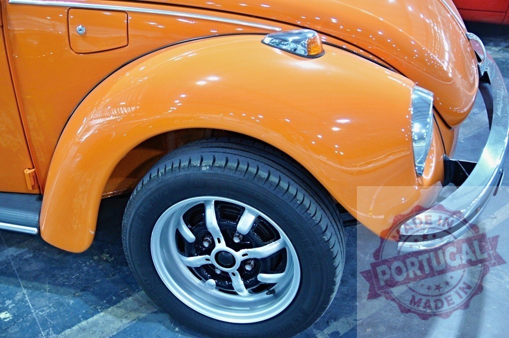 Orange Volkswagen Beetle fender, tire and alloy rim detail showing reflections | Close-up of an orange Volkswagen Beetle, highlighting the fender, tire, and alloy rim with prominent reflections - Realized with Pictrs.com