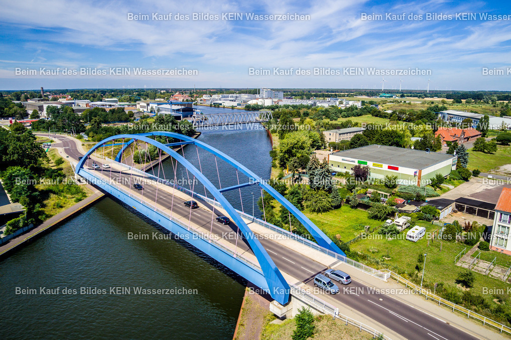 Genthin-0011 | Die Luftaufnahme zeigt Genthin im Landkreis Jerichower Land mit dem Elbe-Havel-Kanal und einer den Kanal querenden Brücke. Die Wasserstraße verläuft durch die von Landwirtschaft und Siedlungsflächen geprägte Landschaft und ist ein wichtiger Bestandteil des regionalen Wasserstraßennetzes. Die Brücke bildet dabei ein markantes Element der Verkehrsinfrastruktur. Aus der Vogelperspektive werden die Verbindung von Kanal, Brückenbauwerk und Stadt besonders deutlich. Die Aufnahme ist Teil des Mitteldeutschen Bildarchivs von Luftbildfotograf Steffen Lehmann. - Realisiert mit Pictrs.com