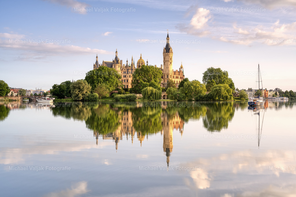 Schweriner Schloss | Blick auf das Schweriner Schloss das vom warmen Licht der frühen Morgensonne angeleuchtet wird und sich im Schweriner See spiegelt. - Realisiert mit Pictrs.com